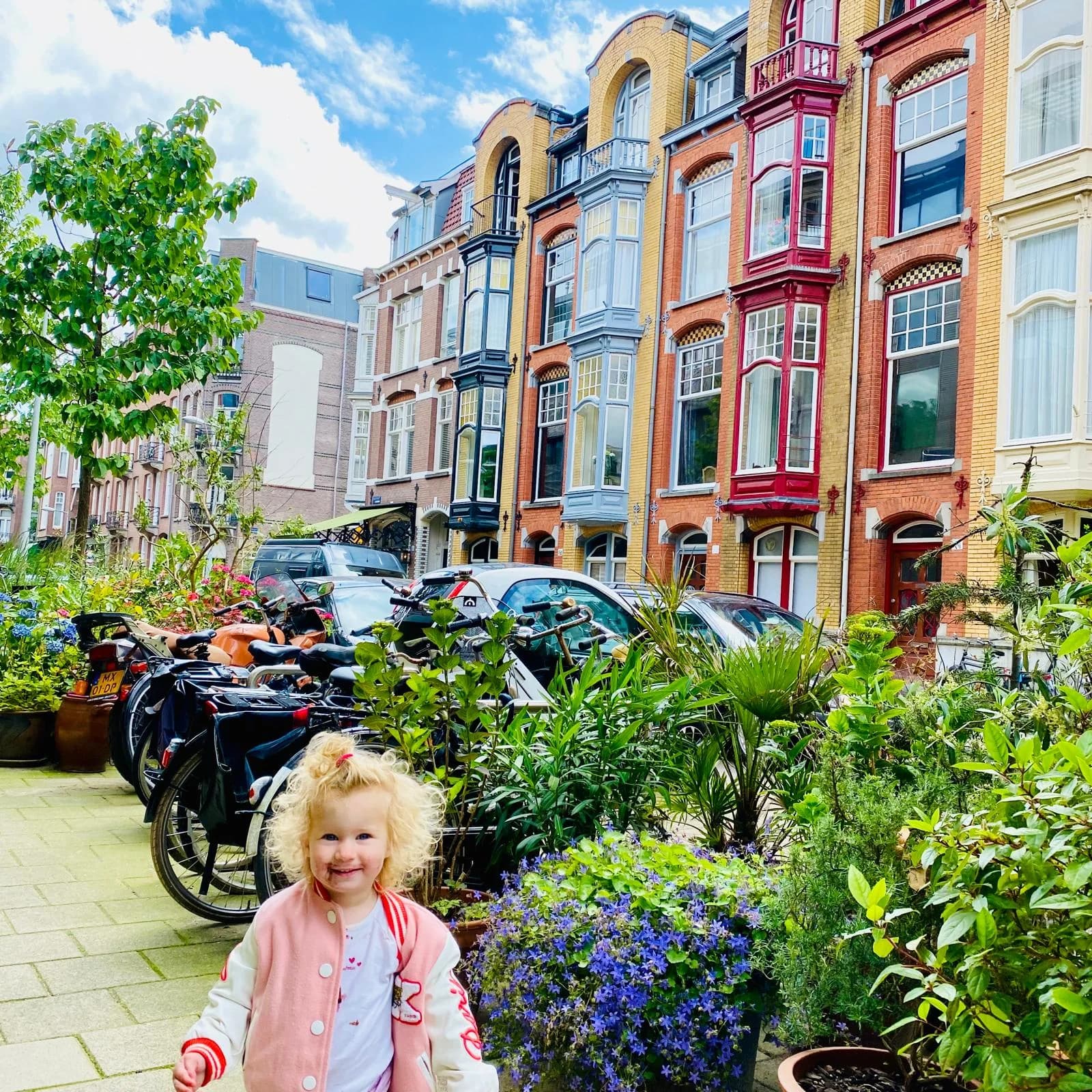 Colourful Dutch houses, bicycles and a child on a green residential street